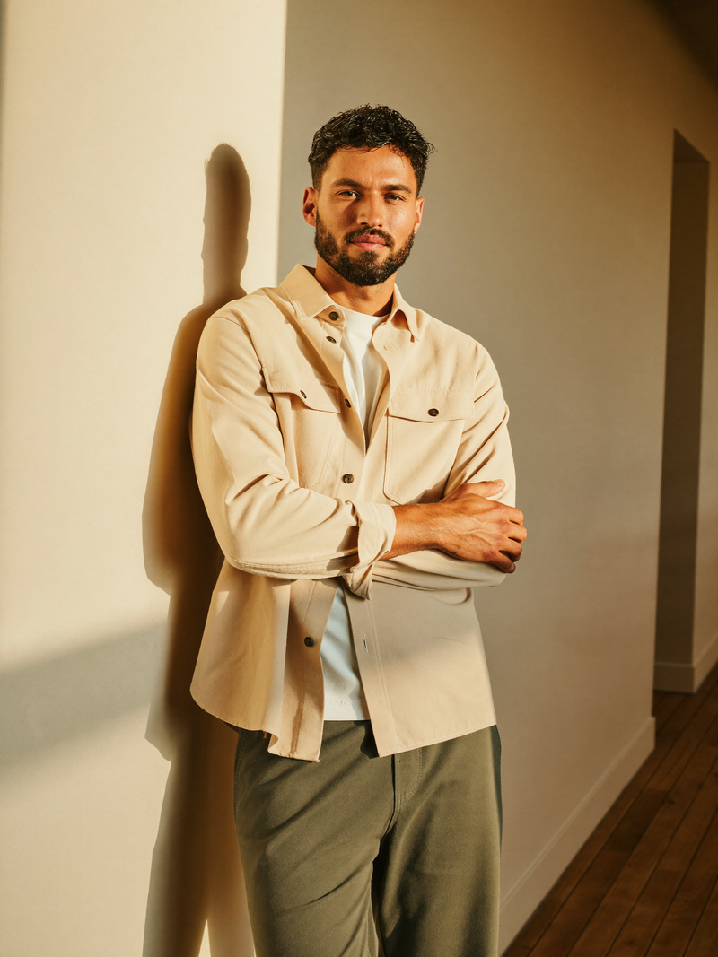 Man in sand overshirt leaning against warm plaster wall