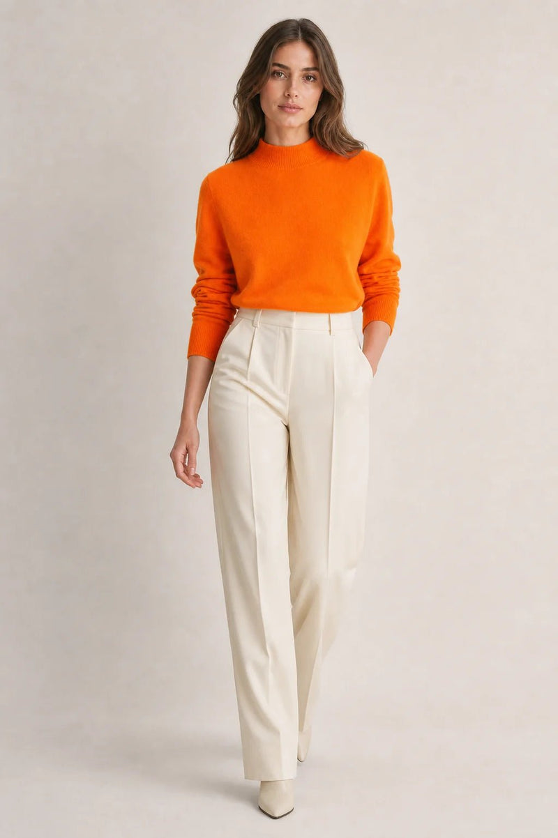 Sofaine Stella mock-neck knit sweater in bright orange with cream trousers, styled full look